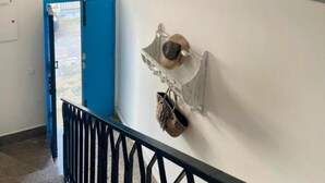 Un couloir avec une porte bleue, un mur blanc et une rambarde noire.