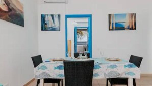 Un comedor con una mesa dispuesta para cuatro personas, rodeada de sillas, y obras de arte en las paredes.
