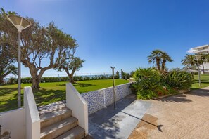 Un escalier menant à une terrasse d’où l’on peut admirer la mer, un mur recouvert de carreaux et un lampadaire.