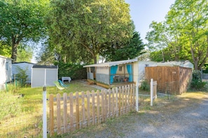 A mobile home with a fenced yard, a small deck, and a covered outdoor area.