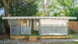 A small, single-story cabin with a porch, a door, and a window. - Mobile home in La Tremblade – Private garden, terrace, playground, and shared pool (La Tremblade (17390))