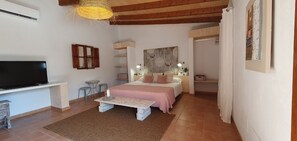 Una camera da letto con un letto, comodini, una TV e una lampada a sospensione.