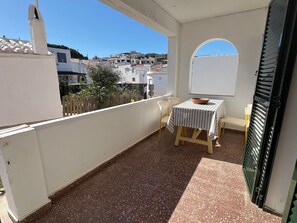 Un balcon avec une table et des chaises, une vue sur les bâtiments et une porte.