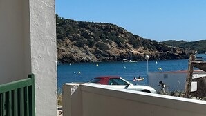 Un balcón con mesa, sillas y vista al mar, además de una costa rocosa.