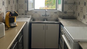 Cocina compacta con ventana, cafetera y estufa.