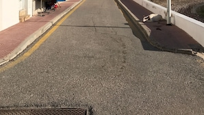 Una calle con un cartel de ‘no estacionar’, un edificio con una tienda a la izquierda y un poste de luz a la derecha.