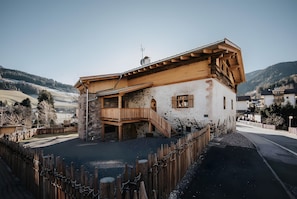 Un edificio rústico con balcón de madera, base de piedra y vistas despejadas del paisaje circundante.