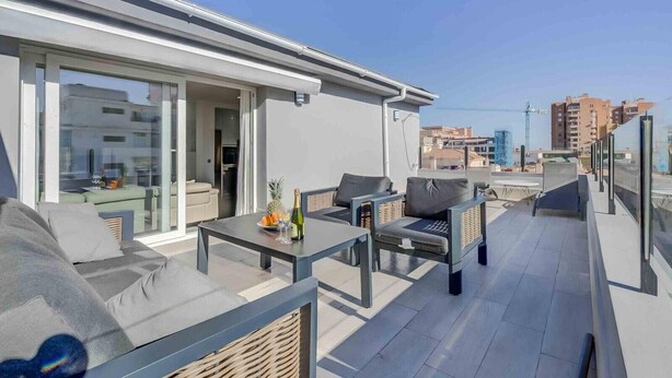 Une terrasse sur le toit avec des sièges en plein air, une table avec des boissons et une vue sur le paysage urbain.