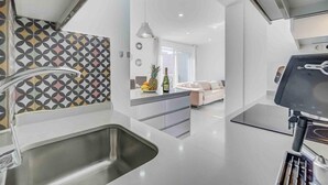 Une cuisine moderne dotée d’un évier en acier inoxydable, d’un crédence décorée et d’un coin repas comprenant un canapé et une table.