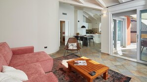 Una sala de estar con un sofá rojo, una mesa de centro de madera y una zona de comedor con mesa y sillas.