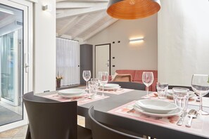 Un coin repas avec une table dressée pour quatre personnes, un canapé et une grande fenêtre.