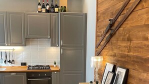Une cuisine avec des meubles de couleur grise, un fourneau et un mur en bois agrémenté d’une échelle rustique.
