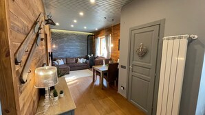Une pièce chaleureuse avec un mur en bois, un canapé, une table à manger et une porte grise.