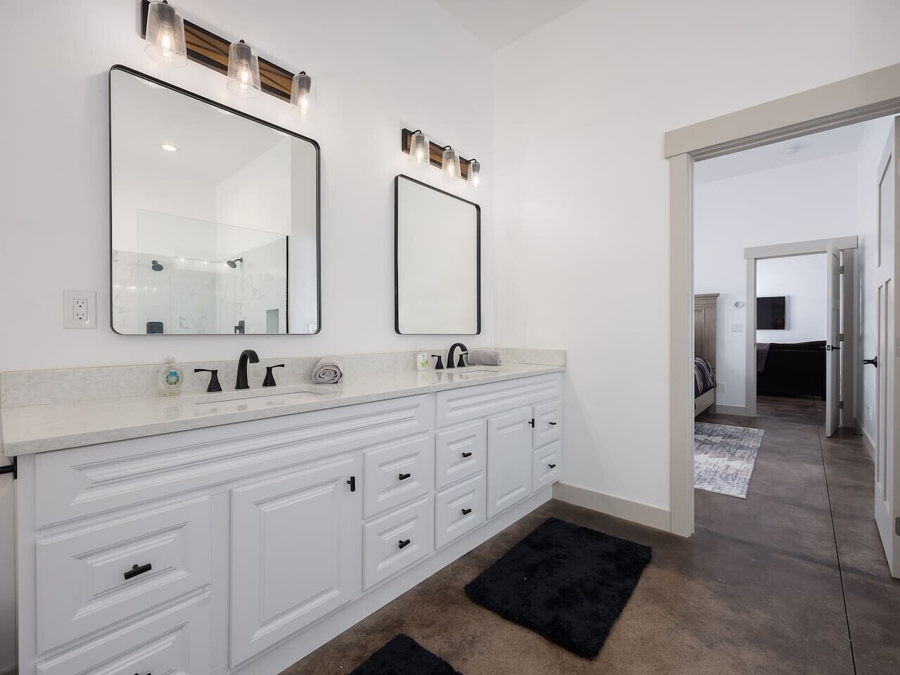 A modern bathroom with a large vanity, two mirrors, and a walk-in shower.