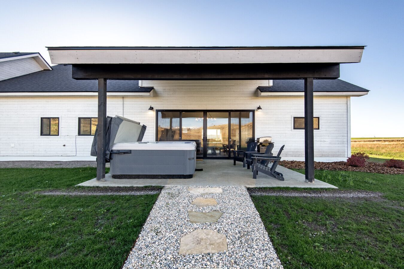 A modern house with a covered patio, a hot tub, and outdoor furniture.