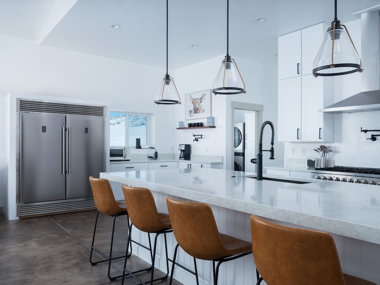 A modern kitchen with a large island, stainless steel appliances, and pendant lighting.