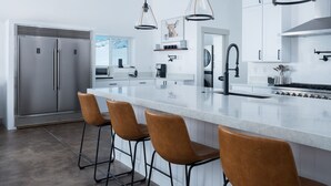 A modern kitchen with a large island, stainless steel appliances, and pendant lighting. - Elk Run Ranch With Hot Tub (Tetonia)
