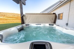 Un bain à remous doté d’un couvercle beige, d’une fenêtre et offrant une vue sur un champ verdoyant.