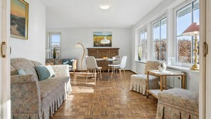 A spacious room with a herringbone wooden floor, a dining table with chairs, a sofa, and a small table with a lamp. - Beautiful home in Nibe with sauna (Nibe)