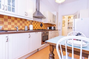 A kitchen with white cabinets, a checkered backsplash, a stove, oven, and a dining table with chairs. - Elegantis.it Solinda Suite Apartment with Private Terrace - Metro, Tram & Bus (Roma)