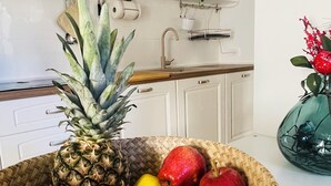 A kitchen with white cabinets, a microwave, and a fruit basket containing pineapple, apples, oranges, and lemons. - Cozy suite ideally located for visiting major sights (Bari)