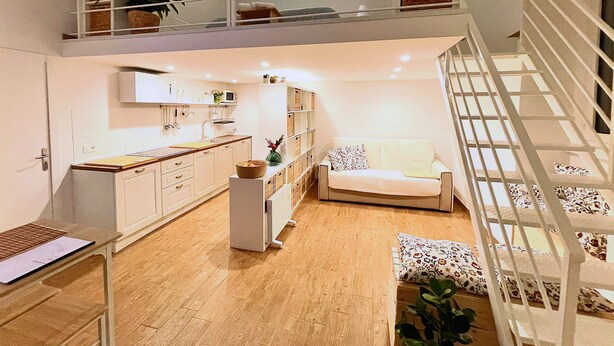 A spacious living area with a high ceiling, a kitchen with white cabinets, a dining table, and a staircase with a railing. - Cozy suite ideally located for visiting major sights (Bari)
