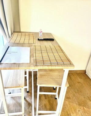 A wooden table with a grid mat, a remote control, a bottle of hand sanitizer, and a document titled "Useful Information English". - A comfortable suite ideally located for visiting the main attractions (Bari)