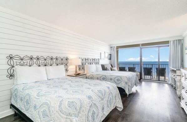 A hotel room with two beds, a balcony with a view, and a dresser. - Sand Dunes 2542 (Myrtle Beach)