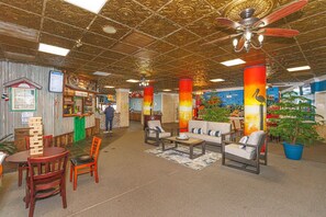 A lobby with a bar area, seating, and a ceiling fan.