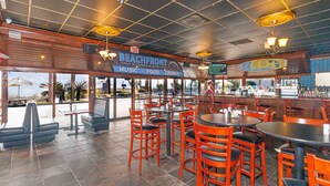 A beach-themed restaurant with outdoor seating, a bar, and a view of the ocean.