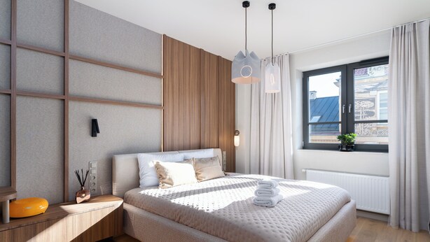 A modern bedroom with a large bed, a bedside table with a lamp, and a window with curtains. - Cracow Superior Apartment (Kraków)