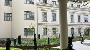 A courtyard with a building featuring multiple windows and a column. - Cracow Superior Apartment (Kraków)