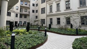 A modern residential building with multiple balconies, a central courtyard with greenery, and a tiled walkway. - Cracow Superior Apartment (Kraków)