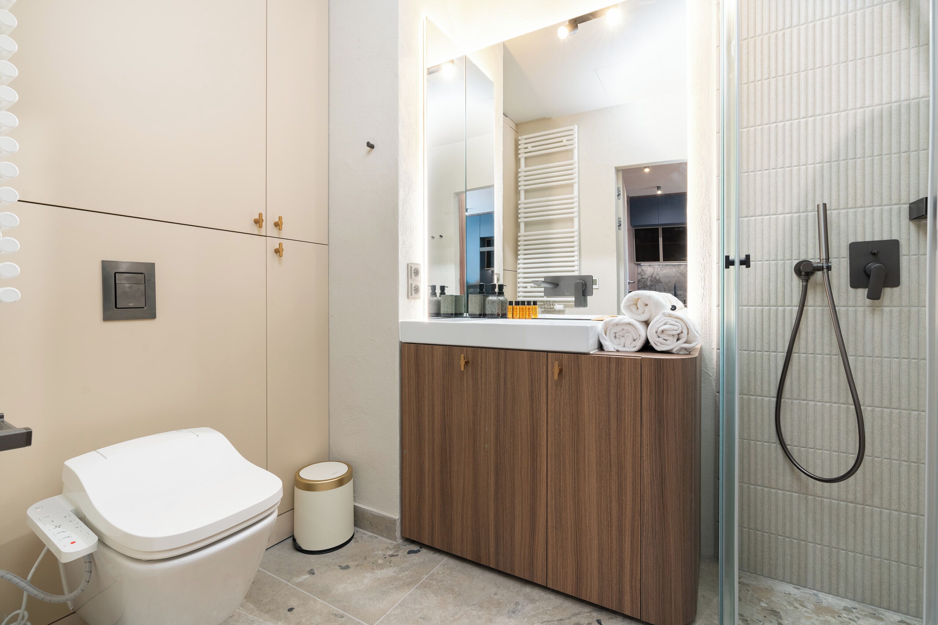 A modern bathroom with a toilet, vanity, mirror, and shower.