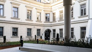 A building with a classical architectural style, featuring a central courtyard with a bench and a column. - Cracow Superior Apartment (Kraków)