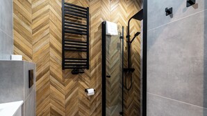 Een moderne badkamer met een wand van visgraat hout, een glazen douchecabine en een wit toilet.