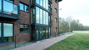 Een modern gebouw met grote ramen, een bakstenen gevel en een verhard voetpad.