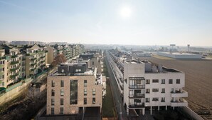 Un moderno complejo de apartamentos con varios edificios, cielo despejado y una vista distante de un paisaje urbano.