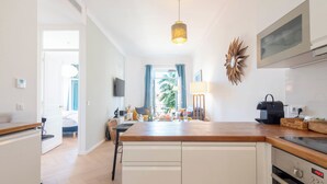 Una cocina moderna con encimera de madera, armarios blancos, horno empotrado y una lámpara colgante.