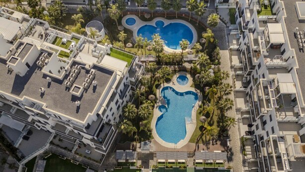 Vue aérienne d’un hôtel doté de plusieurs piscines, d’une terrasse sur le toit et d’un aménagement paysager luxuriant.