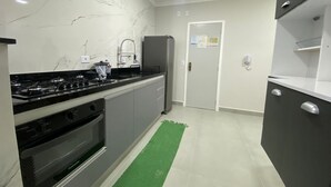 A modern kitchen with a gas stove, oven, and a refrigerator. - Apartment with sea view in Pitangueiras, incredible view, 1 parking space  (Centro Guarujá)