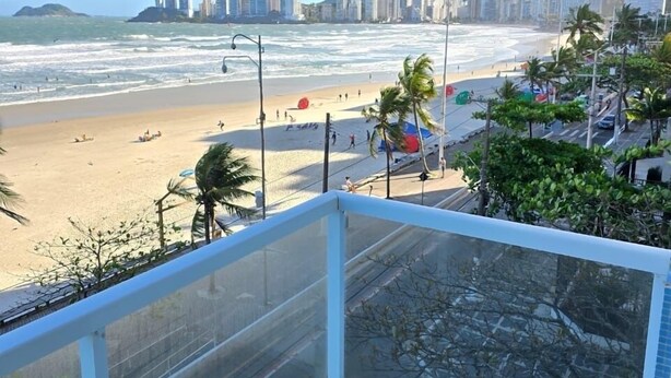 A balcony overlooking a beach with a city skyline in the background. - Apartment with sea view in Pitangueiras, incredible view, 1 parking space  (Centro Guarujá)