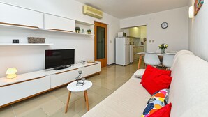 A modern living room with a flat-screen TV, a small white table, and a sofa with red cushions. - Apartment 2372/141541 (Istria - Presika), 5000m from the beach (Presika)