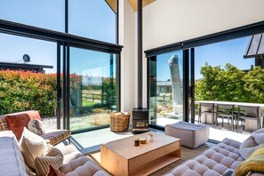 A spacious living area with large windows, a fireplace, and outdoor seating.