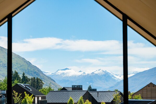 A mountain view through a window with a modern building in the foreground.