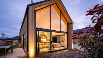 Een modern, gelijkvloers huis met grote glasramen, een houten gevel en een goed verlicht interieur.