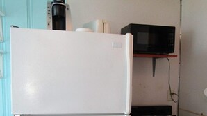 A compact kitchen with a white refrigerator, a black microwave, and a gas stove.