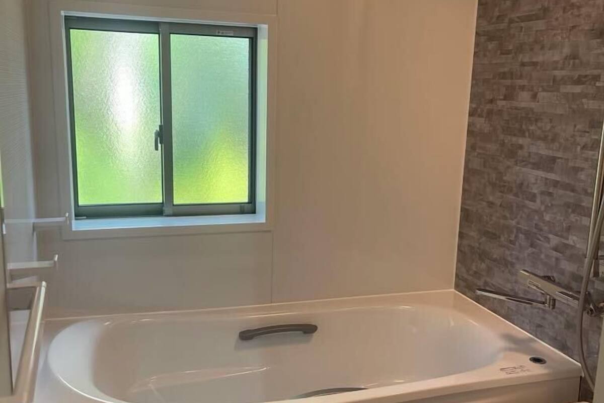 Ein modernes Badezimmer mit einer freistehenden Badewanne, einem Fenster mit Milchglas und einer Duschkabine.