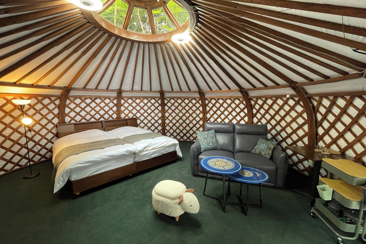 A yurt interior with a bed, sofa, and a small table.