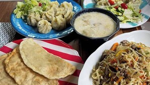 Een tafel met verschillende gerechten, waaronder dumplings, soep en een noodlegerecht.